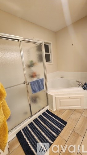 A bathroom with a glass shower door and a white bathtub.