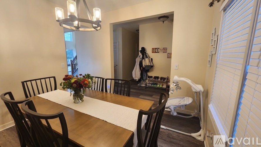 A dining room with a table set for two and a woman standing in the background.