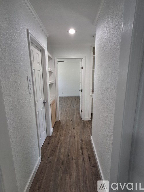A long hallway with white walls and wood flooring.