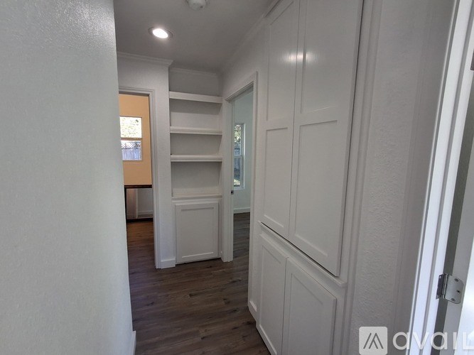 A white paneled room with a doorway leading to another room.