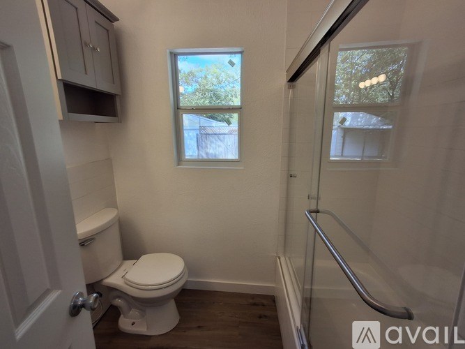A bathroom with a toilet, a window, and a shower.