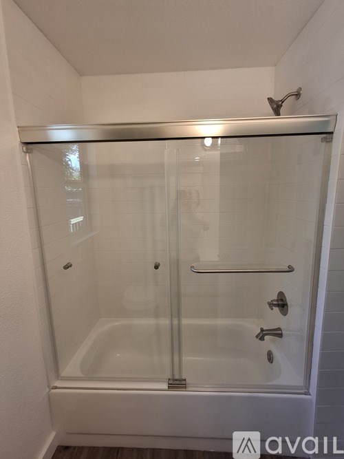 A glass shower stall with a silver handle and a silver shower head.