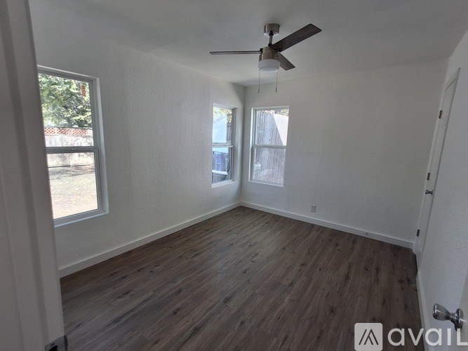 A room with a ceiling fan and wooden flooring.