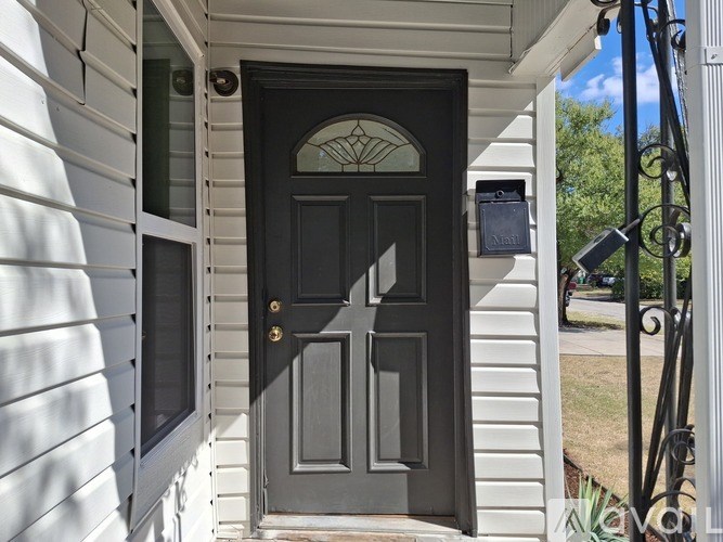 A black door with a glass window is on a white house.