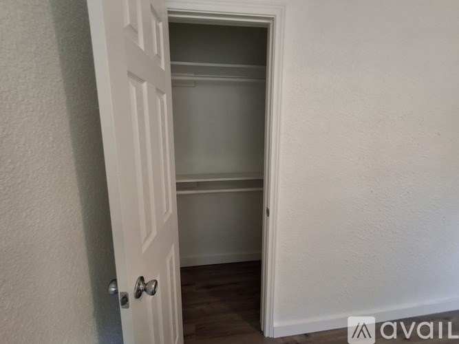 A white door with a glass window is open to a room with a white wall.