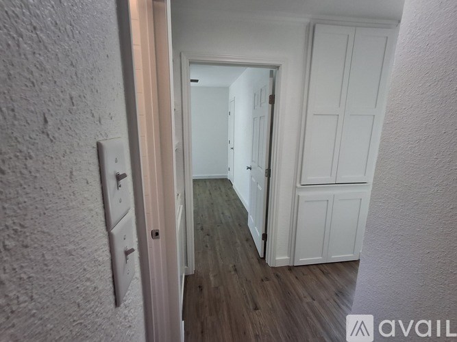 A hallway with a wooden floor and white walls.