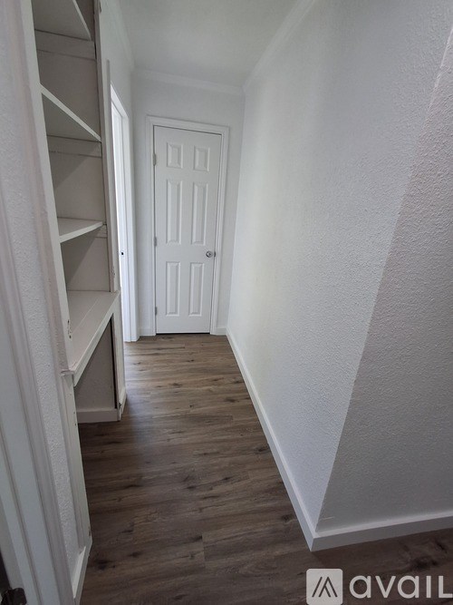 A hallway with a white door and wooden floors.