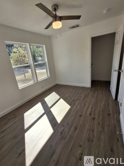 A room with a ceiling fan and wooden flooring.