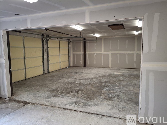 A large empty garage with a yellow door and a white wall.