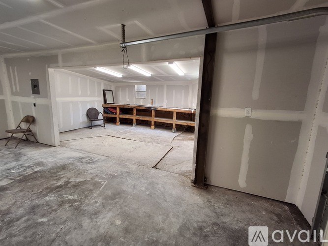 A large empty garage with a workbench and a fan.