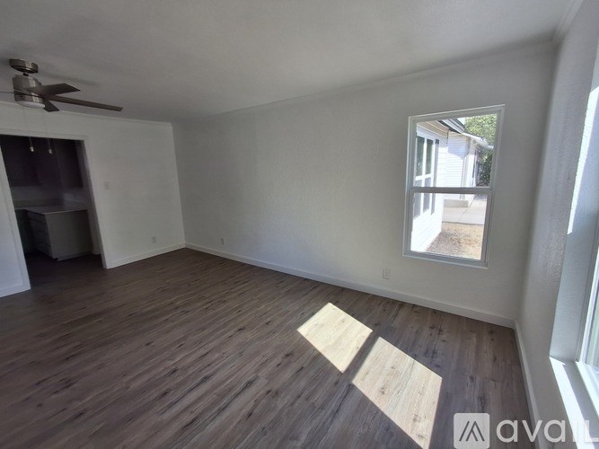 A room with wooden flooring and a window showing an outdoor view.