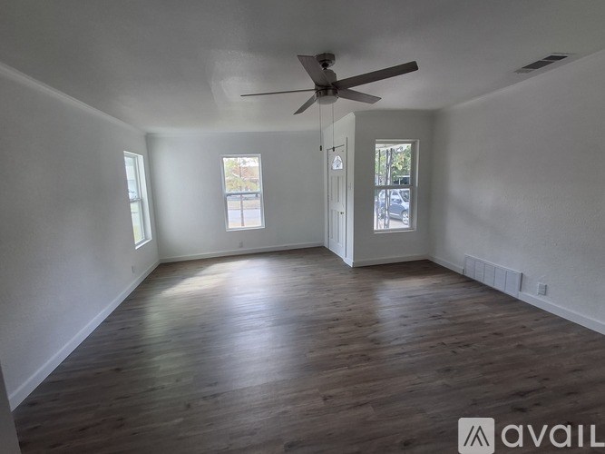 A room with a ceiling fan and wooden flooring.