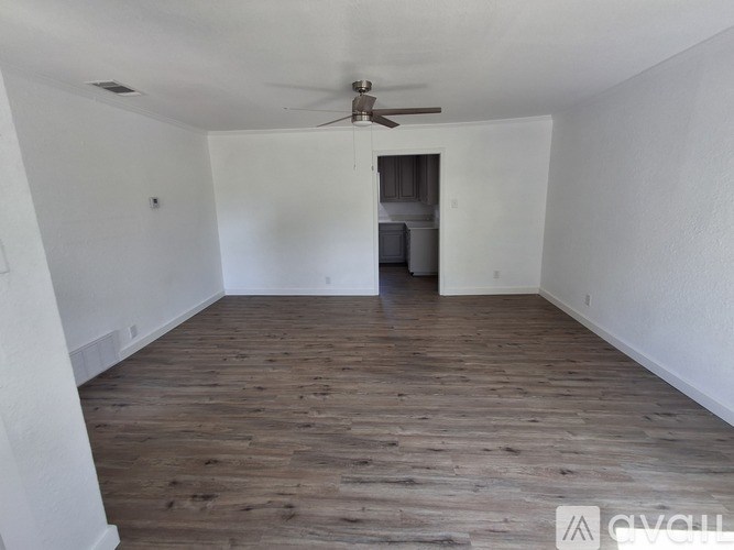 A spacious room with wooden flooring and a ceiling fan.