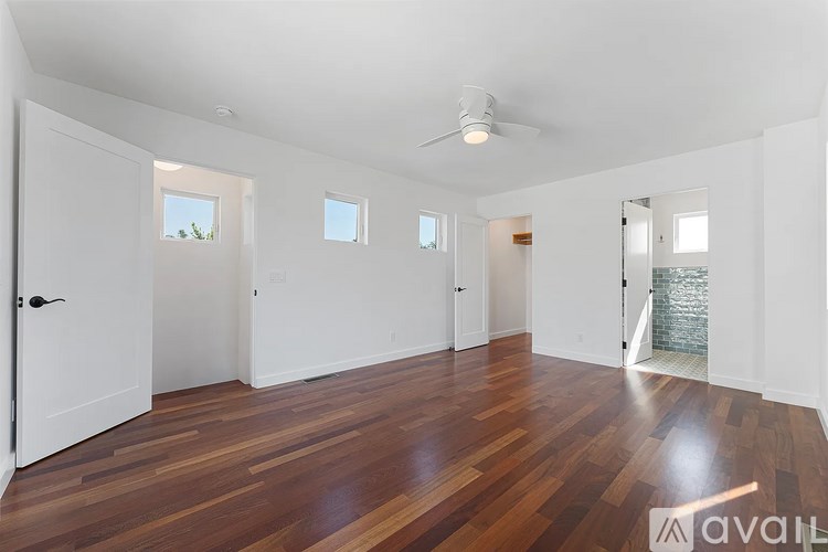 A spacious room with wooden floors and white walls.
