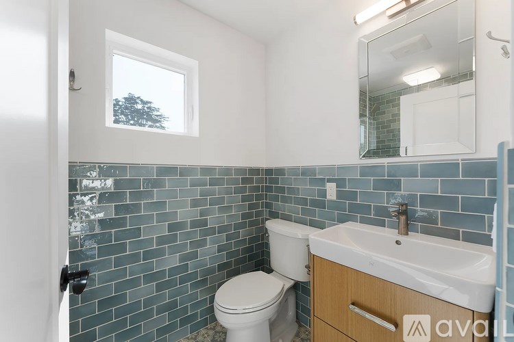 A bathroom with a toilet, sink, and mirror.