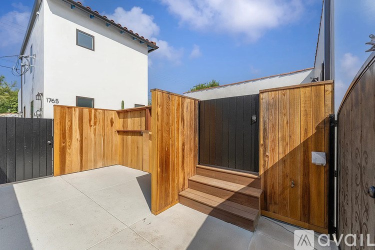 A wooden fence and gate in front of a white house.