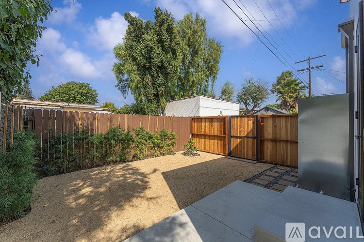 A backyard with a wooden fence and a small tree.