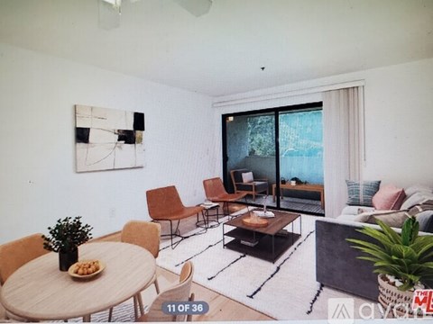 A living room with a table, chairs, and a painting on the wall.