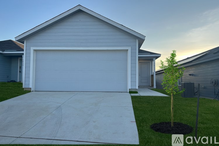 A house with a garage door and a tree in front.