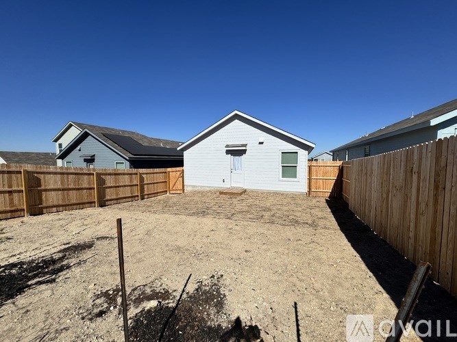 A backyard with a wooden fence and a house in the background.