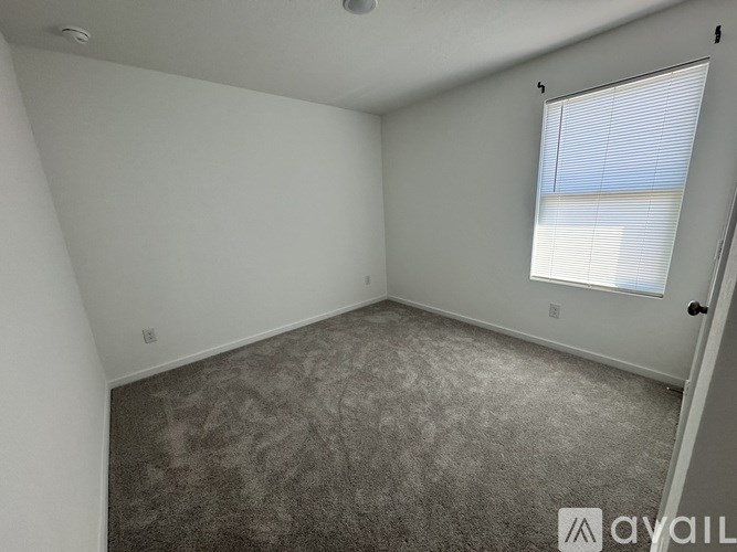 A room with a carpeted floor and a window with blinds.