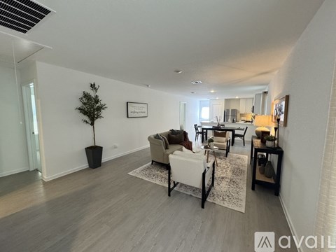 A living room with a white couch and a small tree in a black pot.