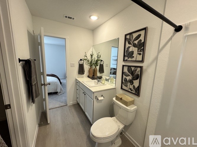 A bathroom with a toilet, sink, mirror, and a plant.