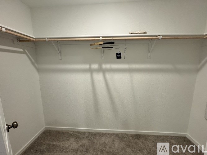 A small, empty room with a carpeted floor and a door on the left side.