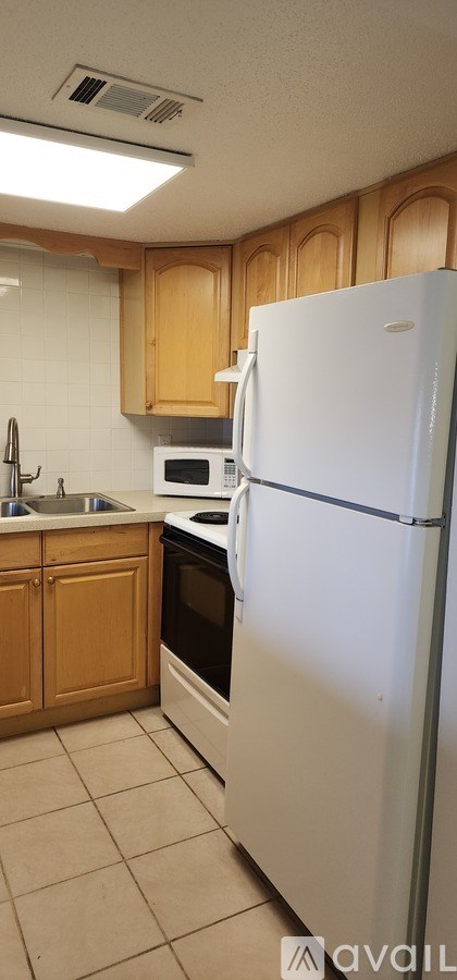 A kitchen with a white refrigerator and wooden cabinets.