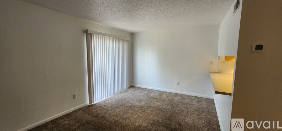 A room with carpeted floor and a window with blinds.