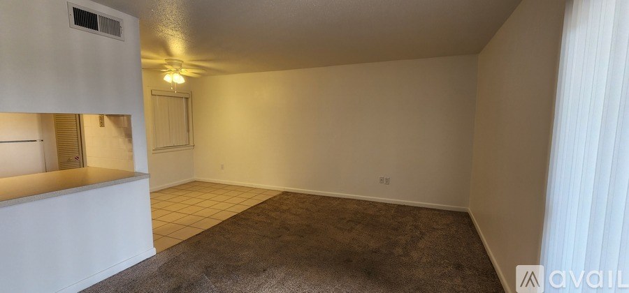 A room with a carpeted floor and a window with blinds.
