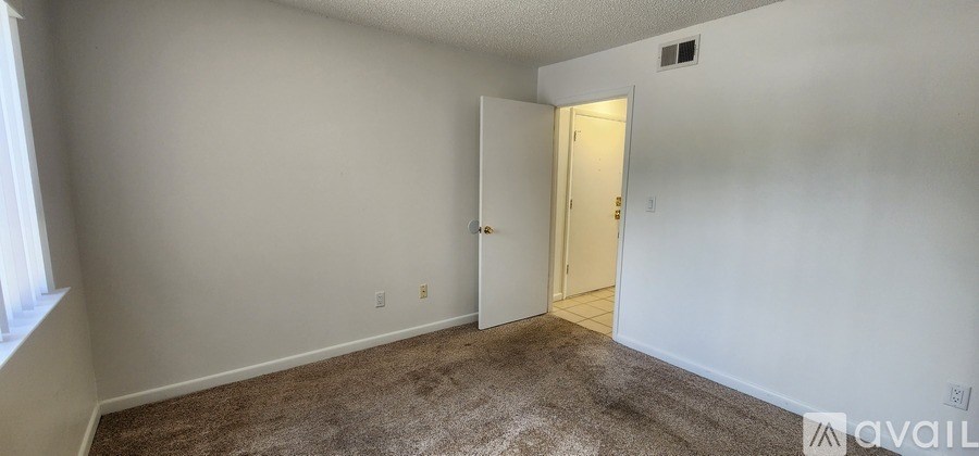 A room with a carpeted floor and a door leading to another room.