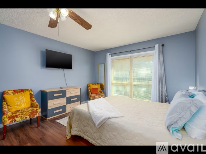 A bedroom with a bed, chair, and a ceiling fan.