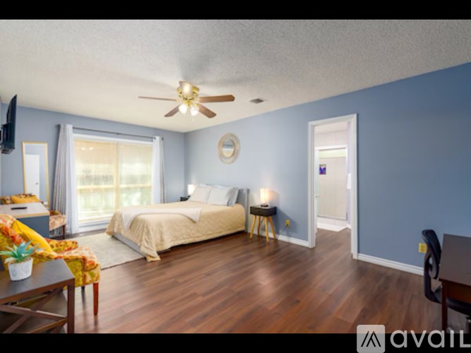 A bedroom with a bed, a chair, and a ceiling fan.
