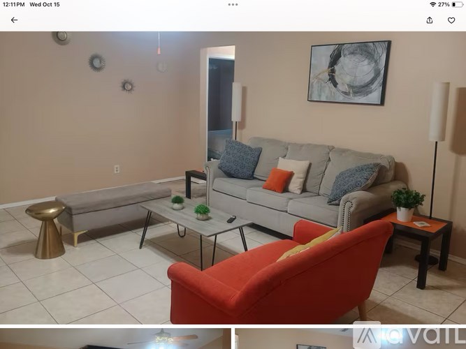 A living room with a grey couch, a red chair, and a gold stool.