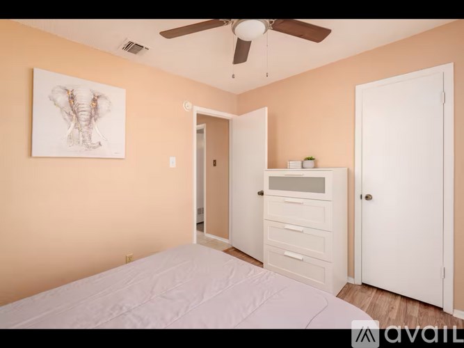 A bedroom with a bed, dresser, and a ceiling fan.