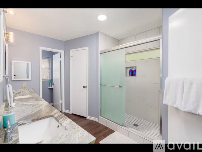 A bathroom with a marble countertop and a glass shower door.