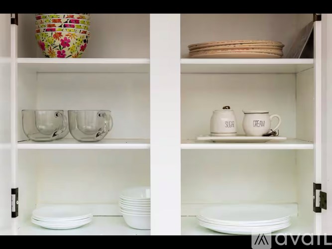 A white cabinet with plates and cups on the shelves.