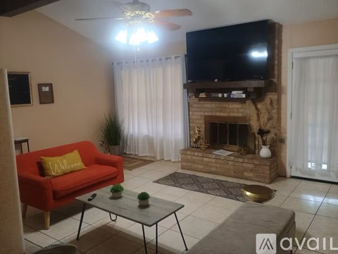 A living room with a red couch, a fireplace, and a television mounted above it.