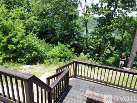 A wooden deck with a railing and a bench overlooking a forested area.