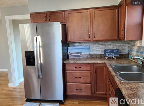 A kitchen with a stainless steel refrigerator and wooden cabinets.