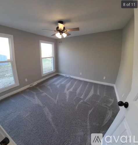 A room with a ceiling fan and carpeted floor.