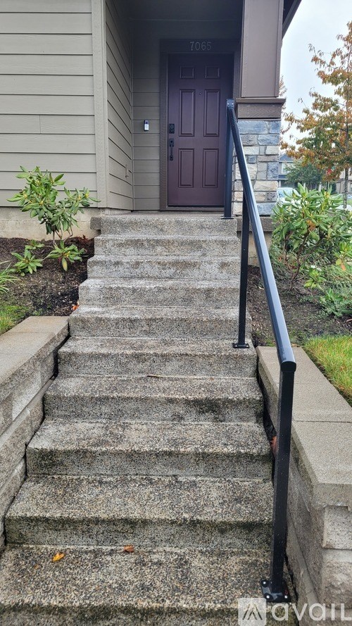A set of stairs leading to a brown door with a black railing on the side.