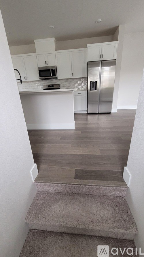 A kitchen with white cabinets and a stainless steel refrigerator.