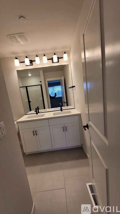 A bathroom with a mirror, sink, and cabinets.