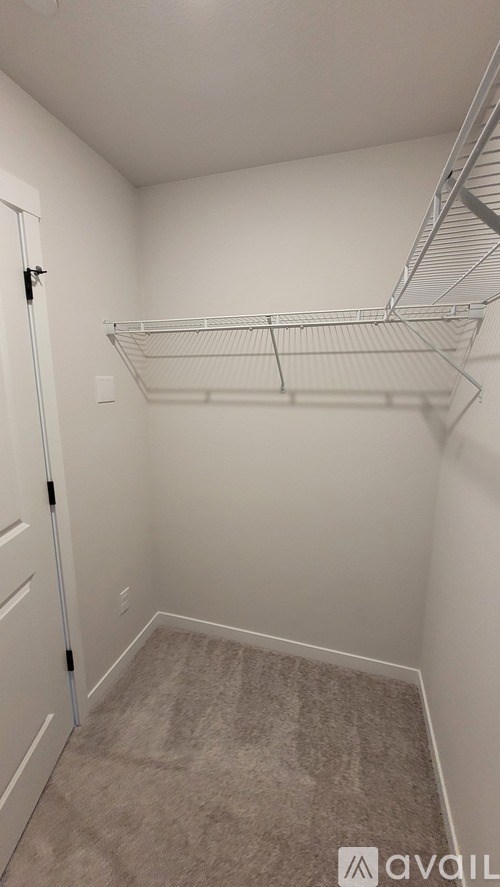 A small, empty room with a carpeted floor and a metal shelving unit.