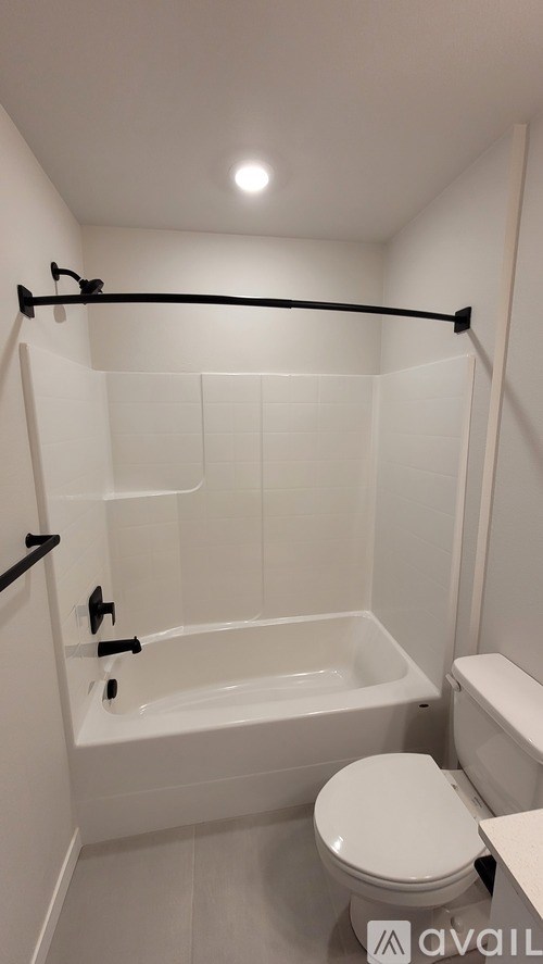 A white bathroom with a toilet, tub, and towel rack.
