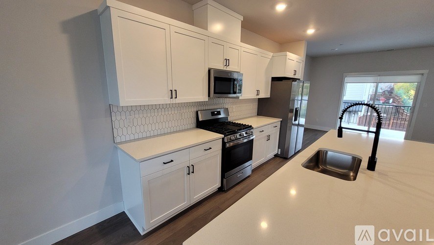 A kitchen with white cabinets and appliances is available for rent.