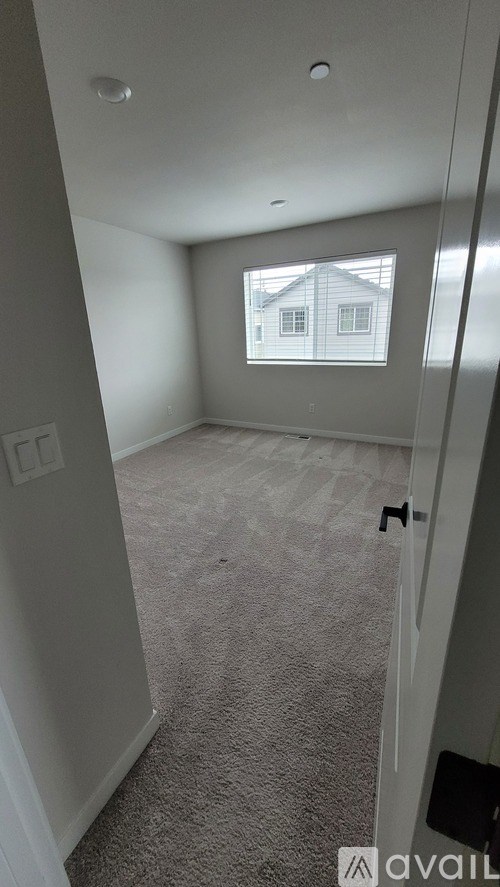 A room with a carpeted floor and a window showing a house outside.