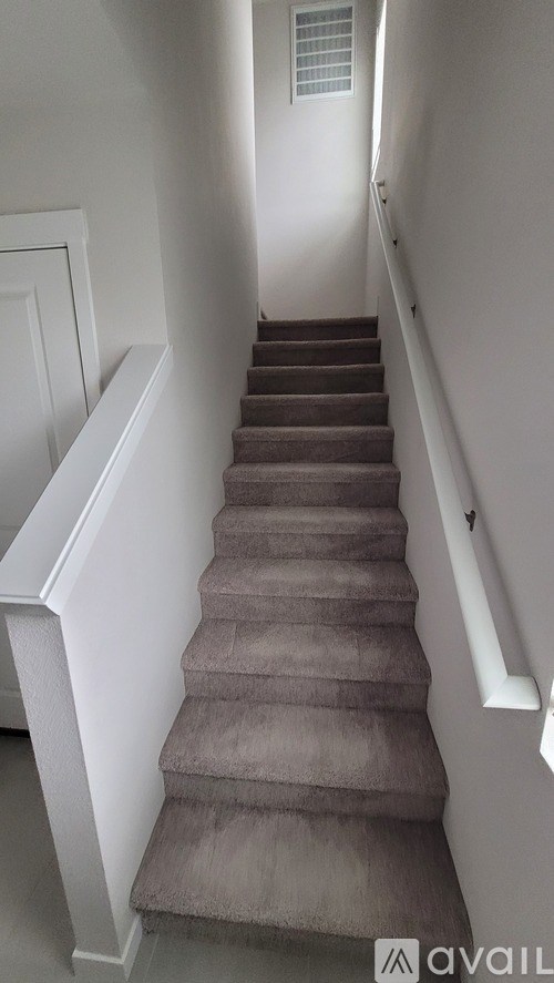 A staircase with a carpeted runner and white walls.